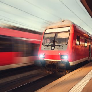 Beautiful railway station with modern red commuter train at colorful sunset in Nuremberg, Germany. Railroad with vintage toning