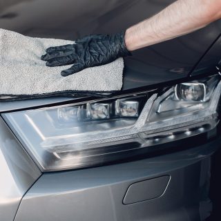 Man in a garage. Worker polish a car.